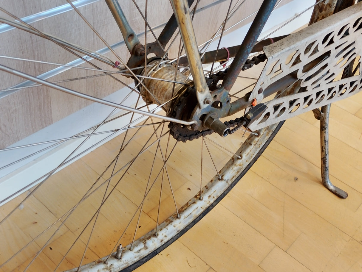 Rostig cykel bakhjul med kedjeskydd och ekrar, närbild