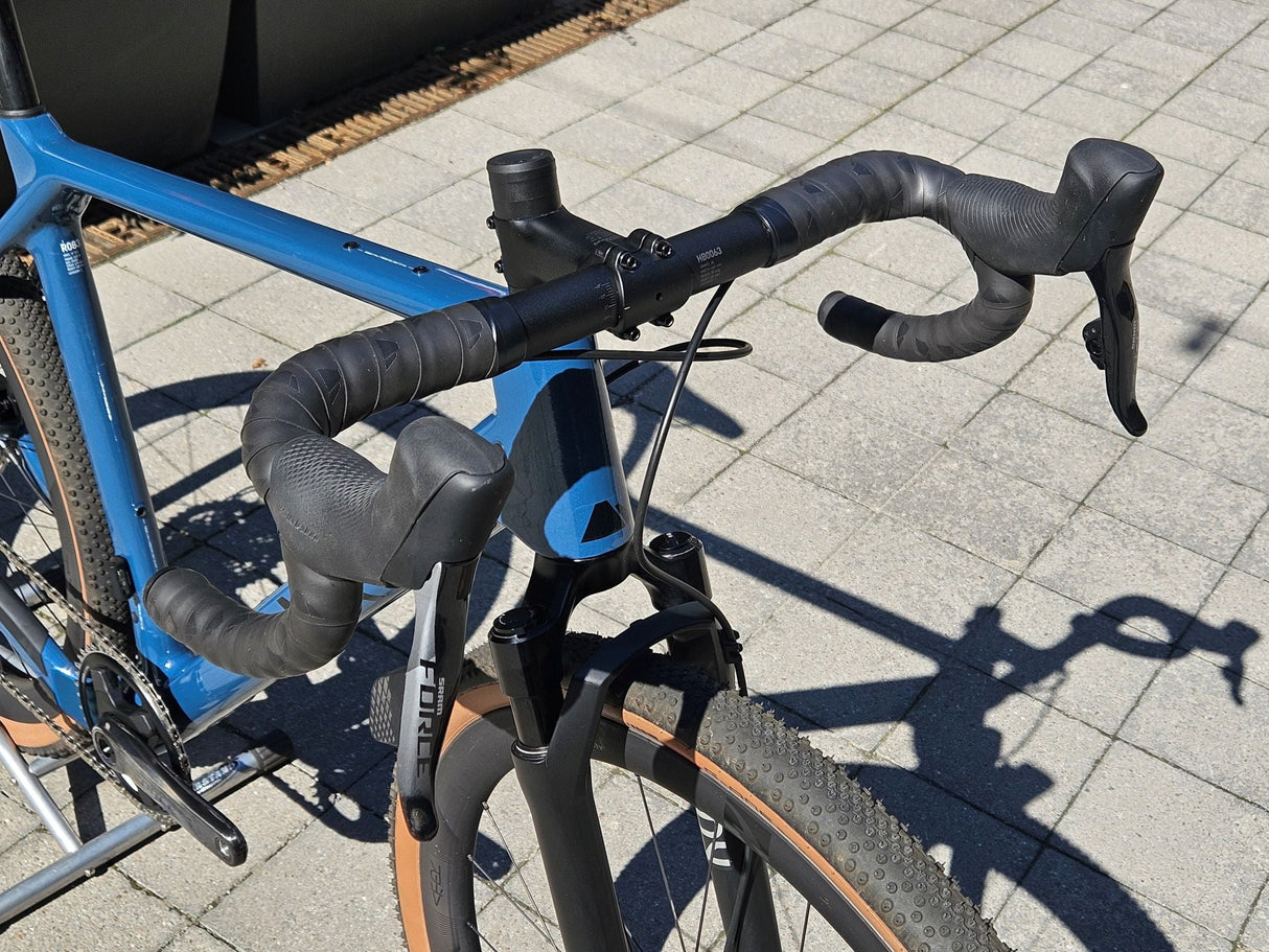 Blå gravelcykel med SRAM Force växelreglage och breda däck, detalj på styret
