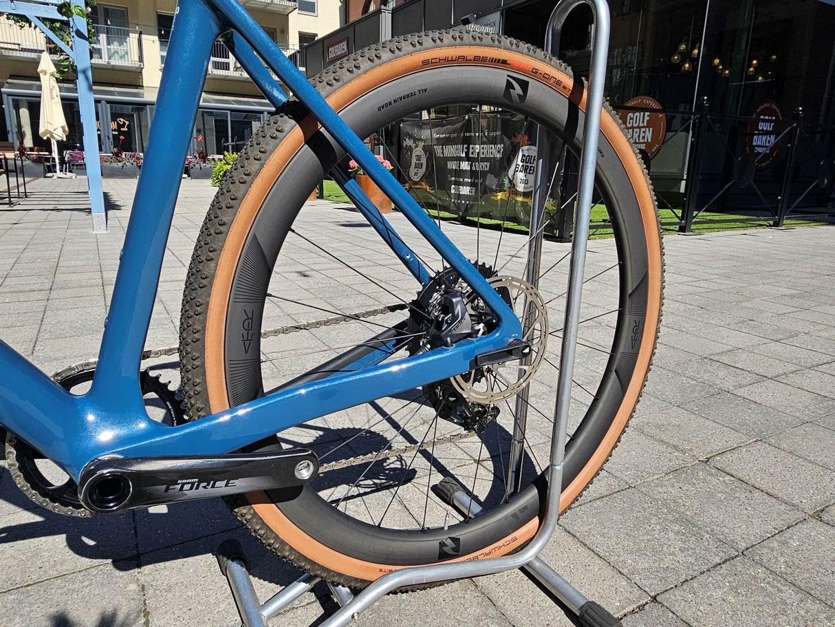Blå gravelcykel med Schwalbe G-One-däck och SRAM Force-växel i cykelställ