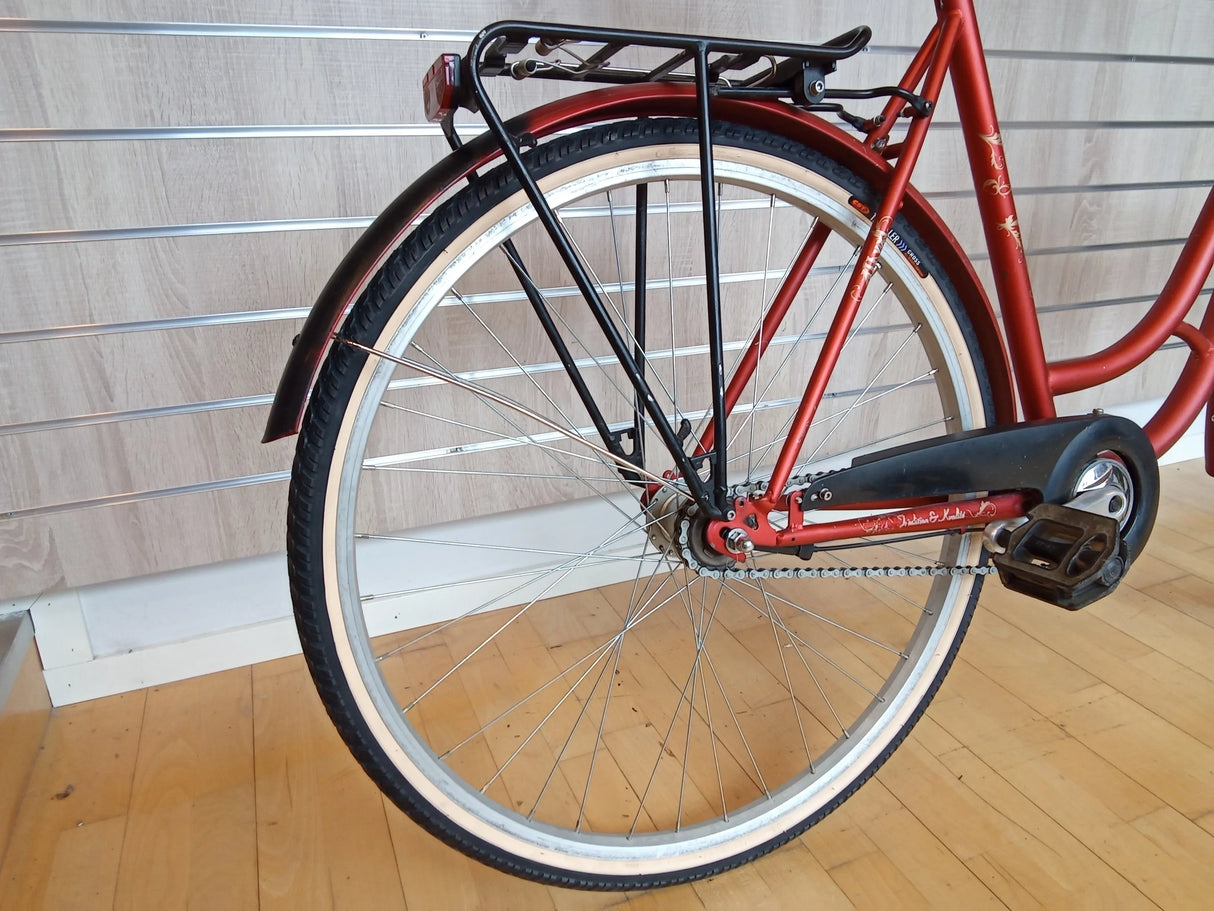 Bakre delen av röd cykel med svart pakethållare, kedja och vitt däck
