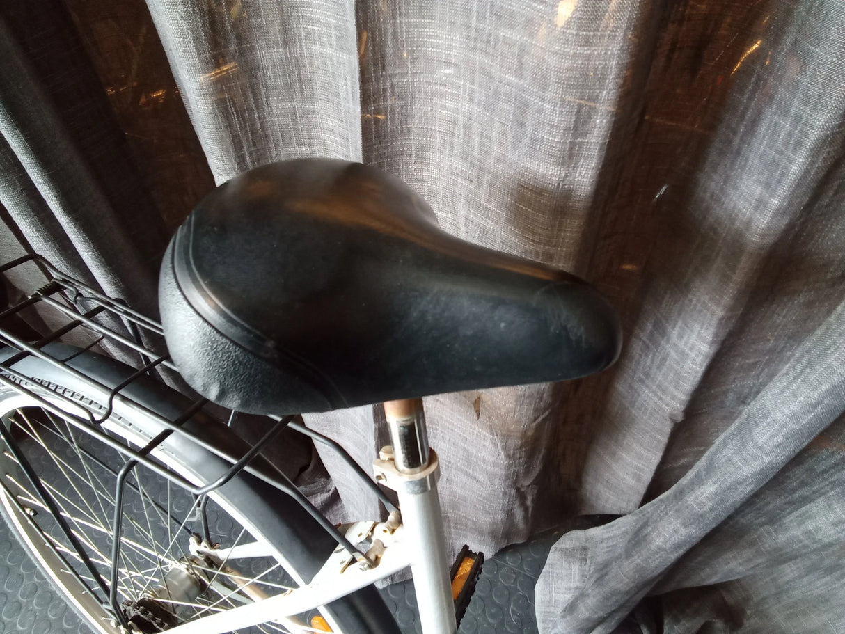 Svart cykelsadel monterad på vit cykel med bakre pakethållare och skärmar