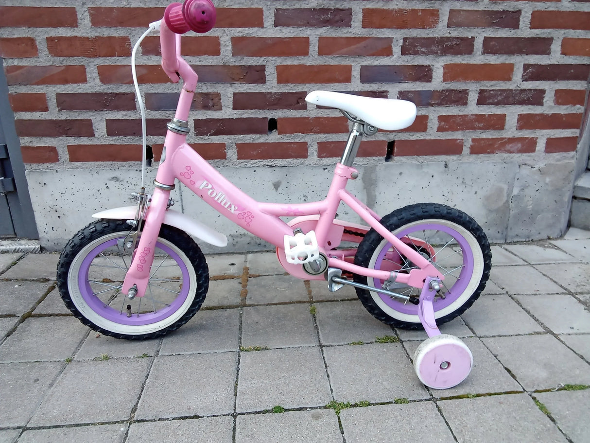 rosa barncykel med stödhjul, vita däckkanter och lila fälgar