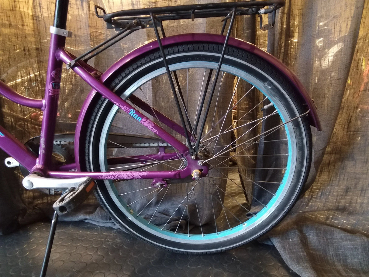 Bakre hjul på lila cykel med turkosfärgad fälg och svart pakethållare