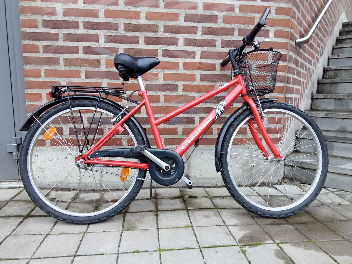 Röd Crescent cykel med svart sadel och framkorg parkerad på trottoar