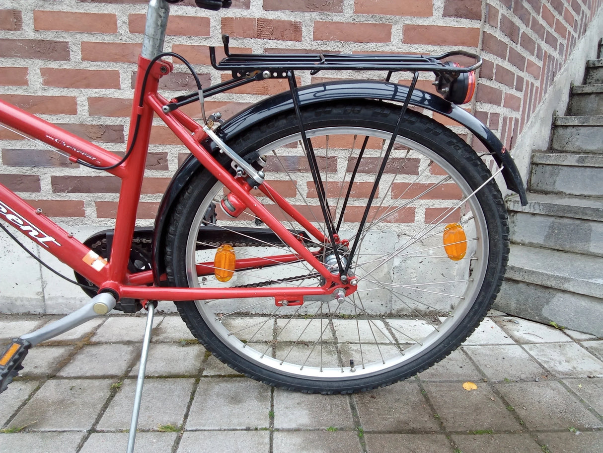 Röd cykel bakhjul med svart pakethållare, reflexer och ställning på stenplattor