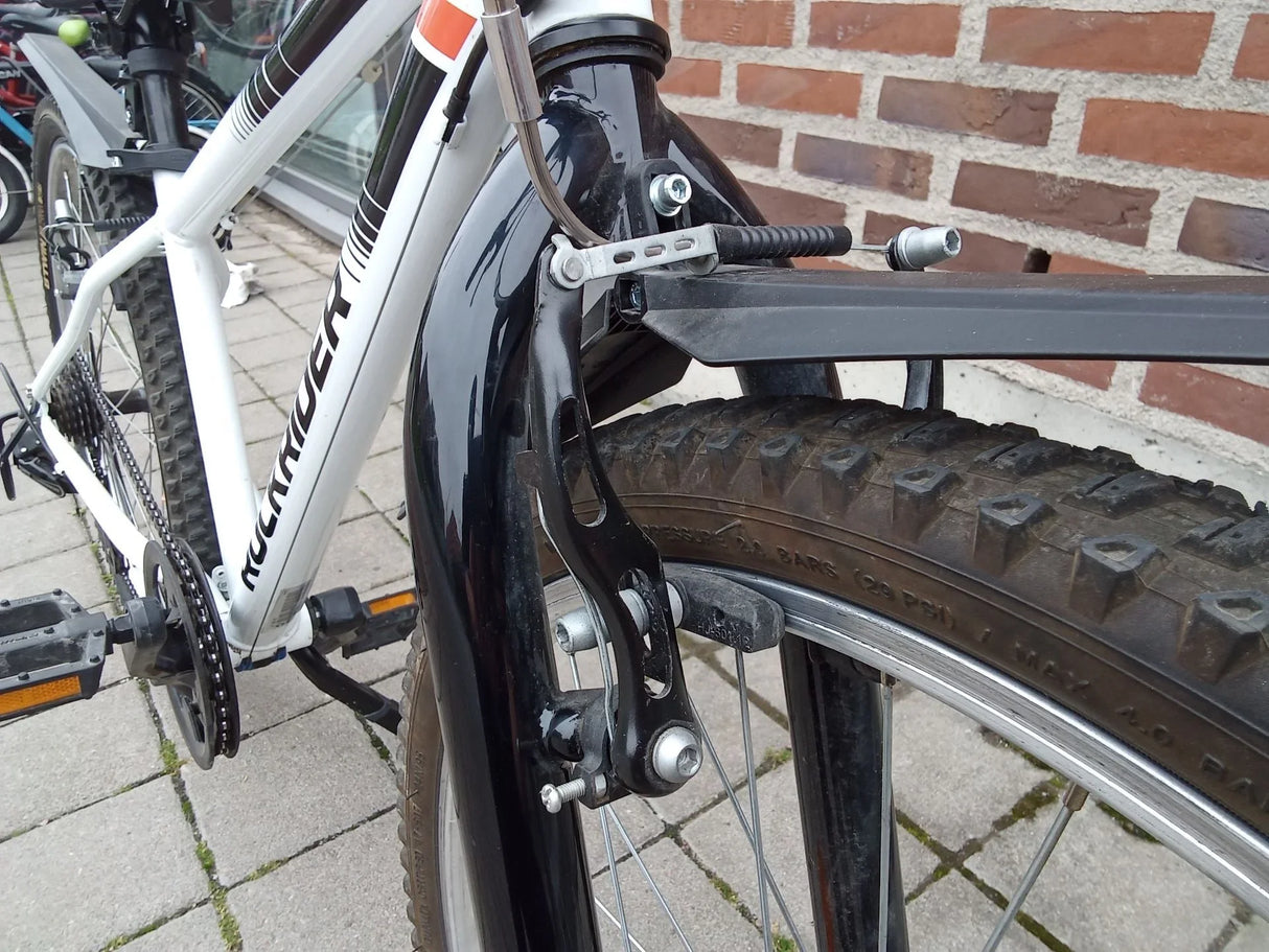 Närbild på mountainbike framdäck med svart fälg och skivbroms, vit ram med texten Rockrider