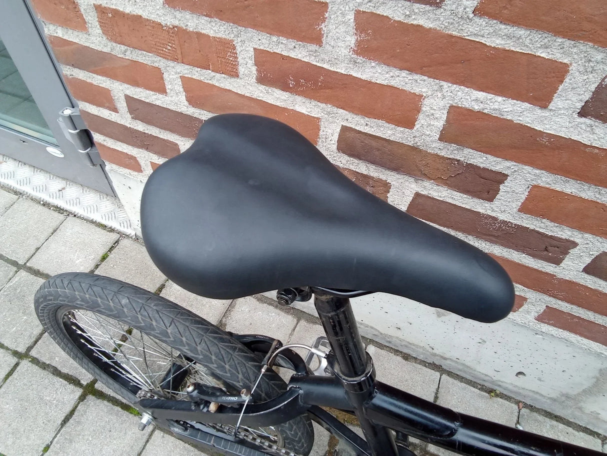 Svart cykelsadel och bakhjul med Tektro broms på stadscykel