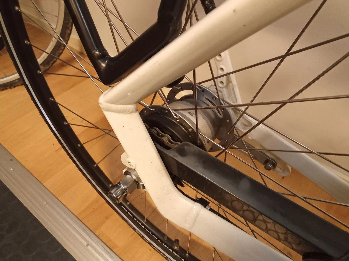 Närbild på cykelns bakhjul med vit ram och svart kedjeskydd