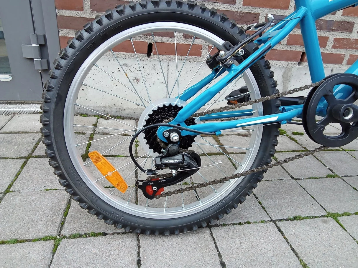Bakre däck och växelmekanism på blå cykel med MTB-däck och kedja