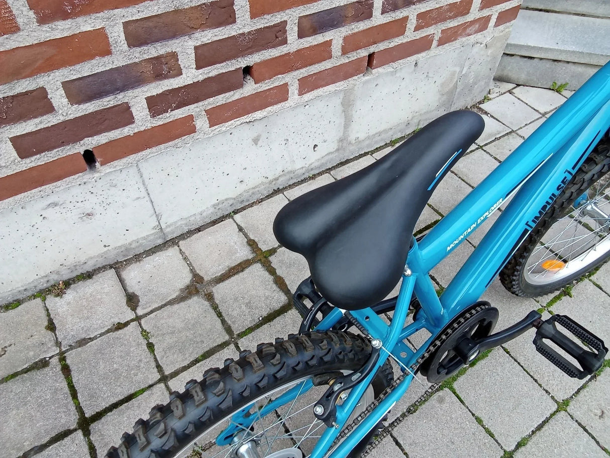 Svart cykelsadel på blå mountainbike med dubbdäck och pedaler