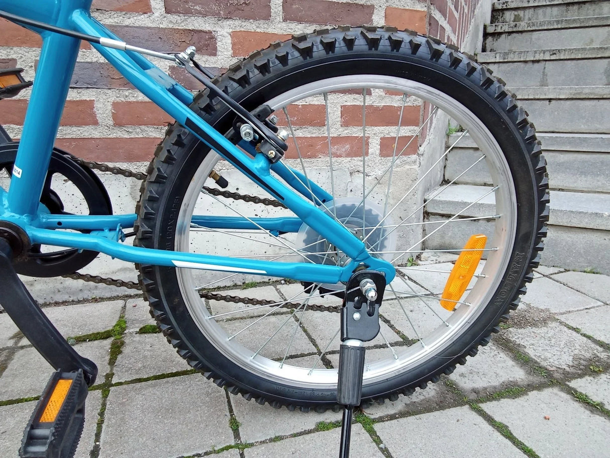 Blå cykel med kraftigt dubbdäck, orange reflexer och kedja på stenlagt underlag