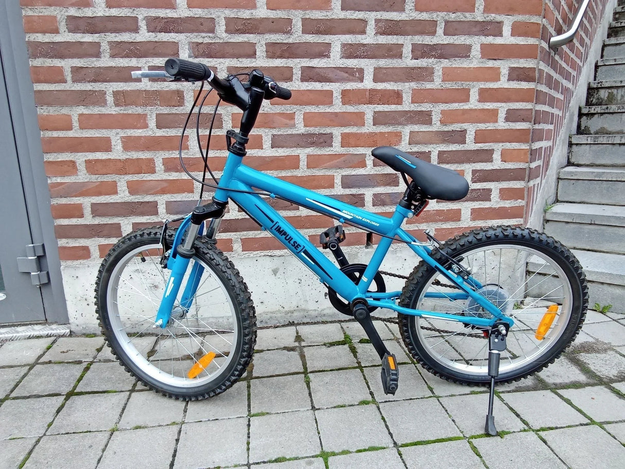 Blå mountainbike med tjocka däck och svart sadel på stenbelagd mark