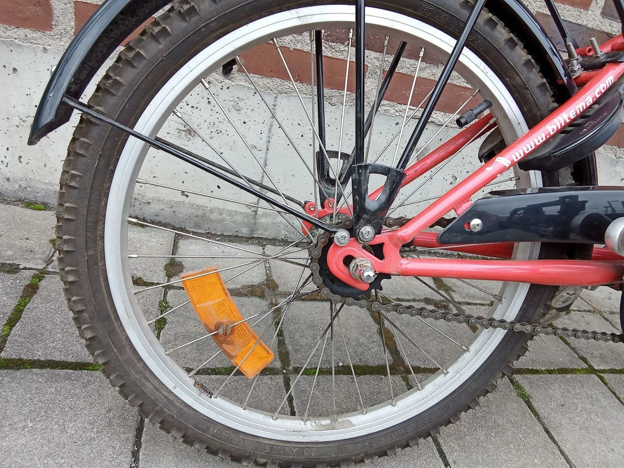 Bakre hjul och kedja på röd cykel med reflex och däck med mönster