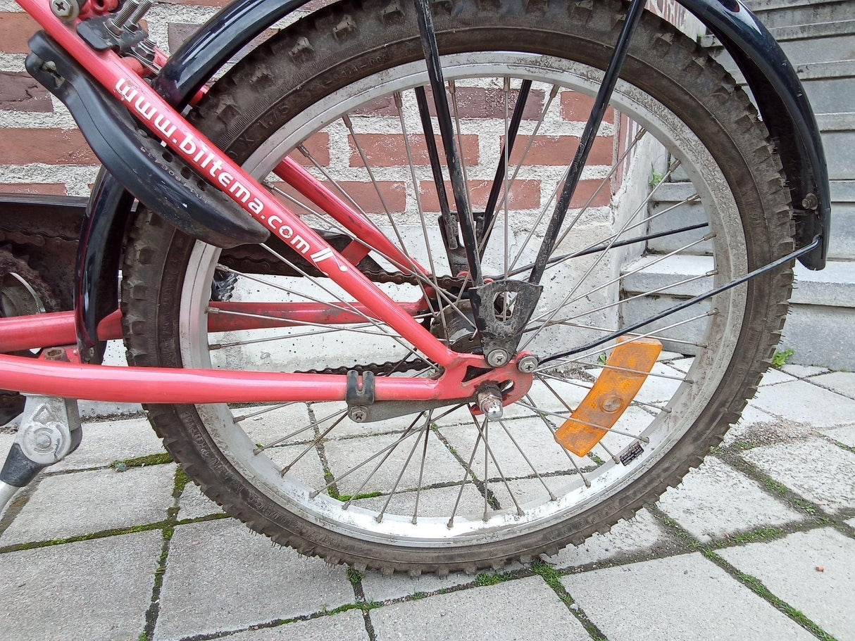 Rött cykelhjul med däcksreflektor och svart stänkskydd, cykelkedja och ram med biltema-logo