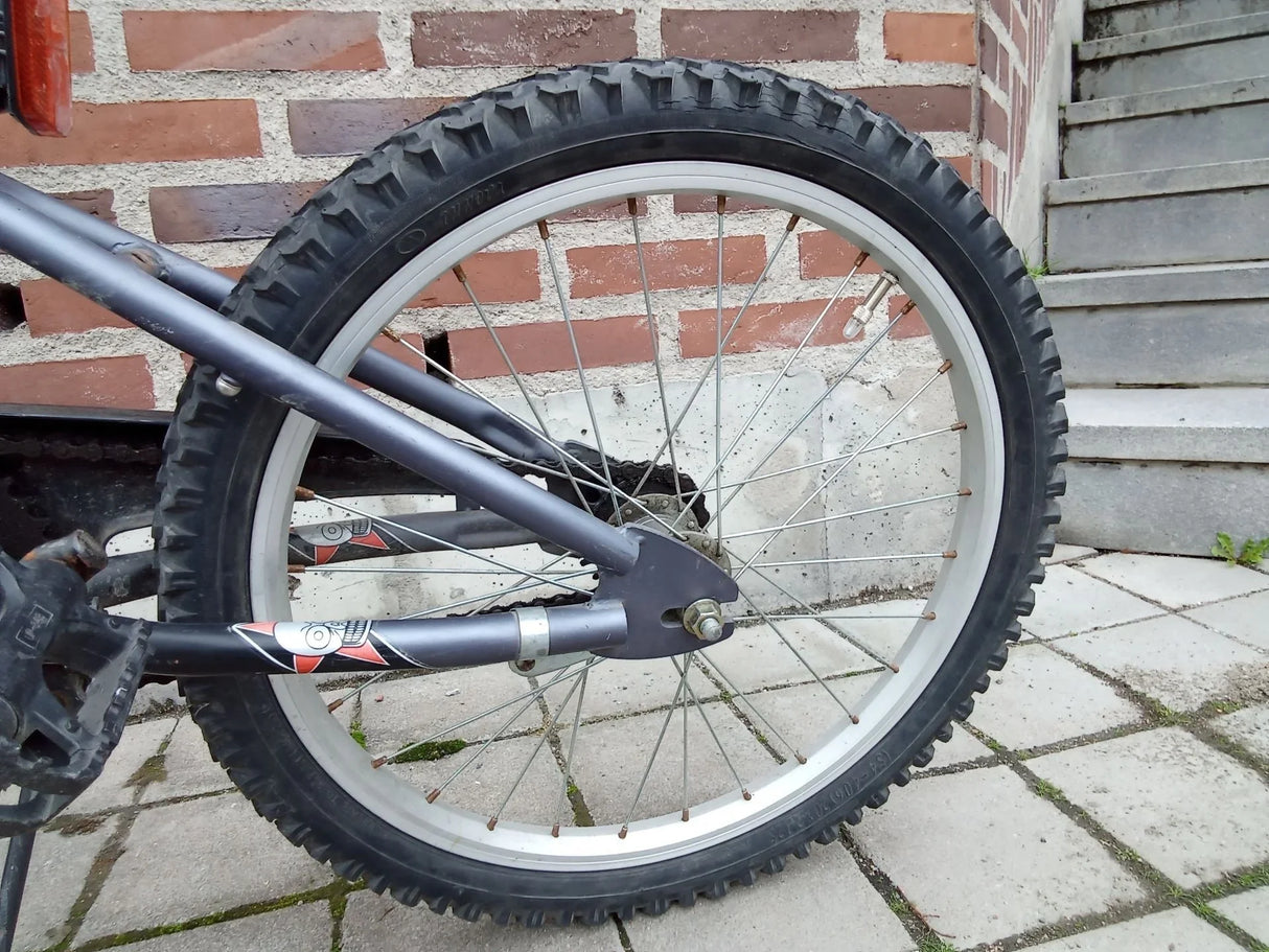 Bakhjul på svart cykel med grovmönstrad däck och silverfärgade ekrar