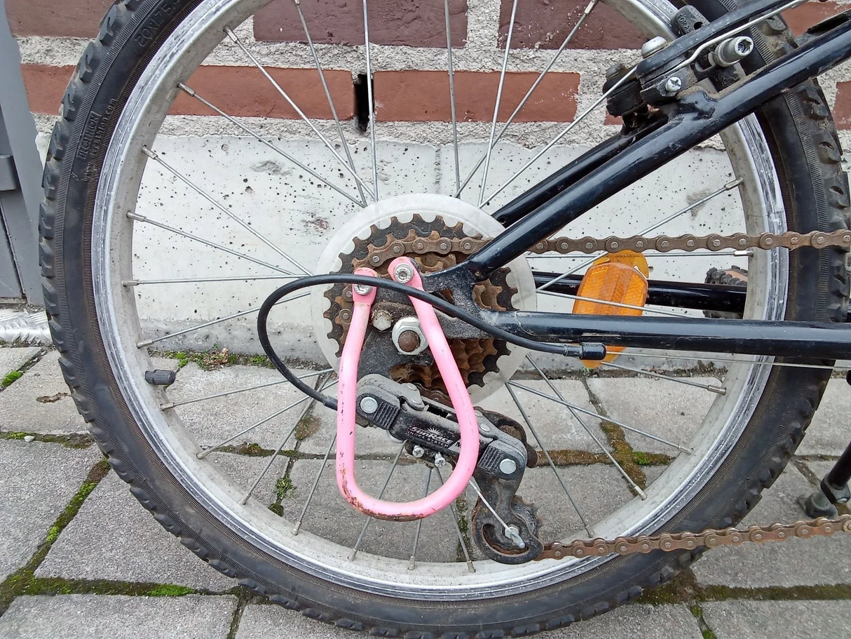 Bicykel bakhjul med rosa lås, kedja och orange reflex på svart cykelram