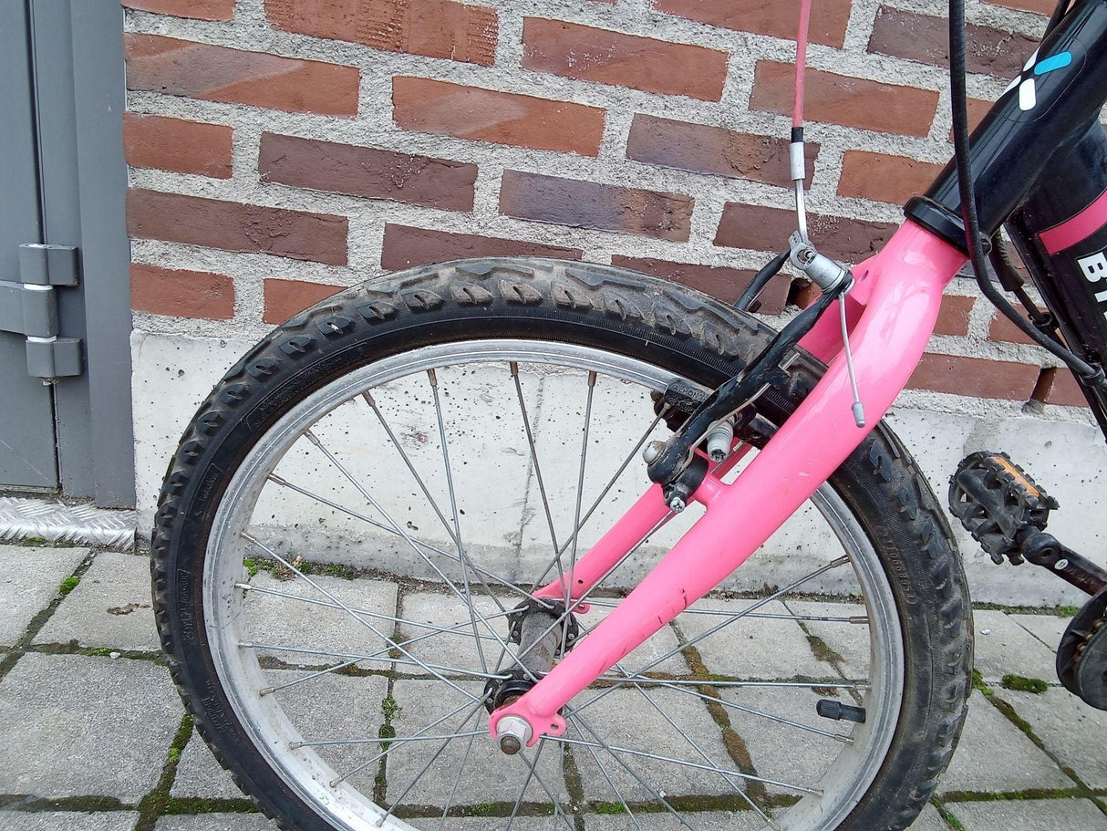 Närbild av framhjul på barncykel med rosa gaffel och svart däck