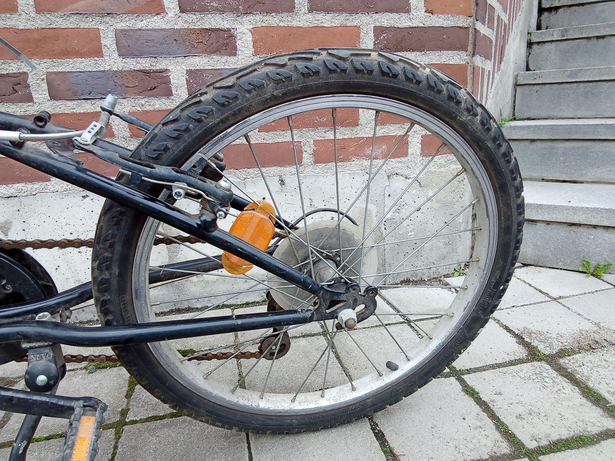 Bakre hjul på svart barncykel med orange reflex och grovmönstrat däck