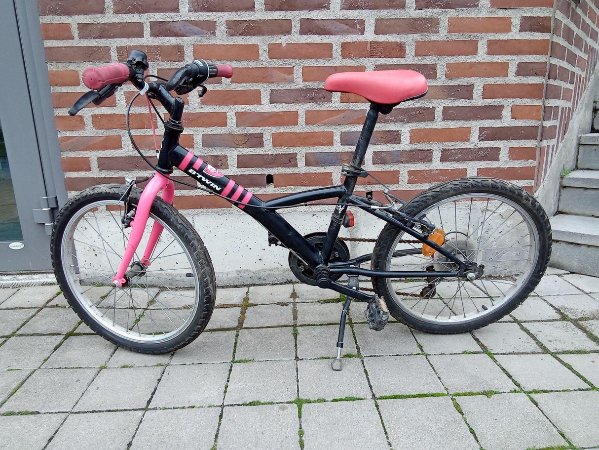 Svart och rosa barncykel med fotstöd och tjocka däck
