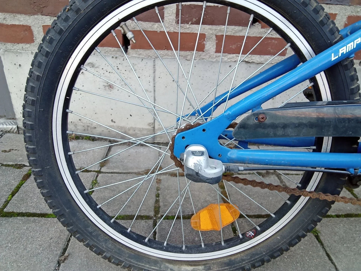 Blå cykel bakhjul med svart däck, kedja och orange reflex