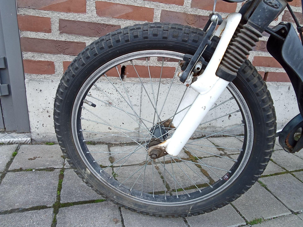 Cykelhjul med svart däck och vit gaffel med fjädring och bromsdetaljer
