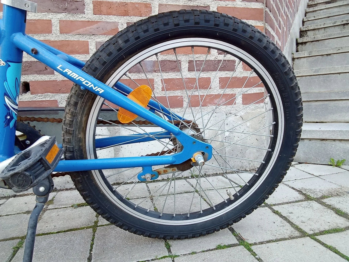 Blå barncykels bakhjul med markeringsreflekter och trampor
