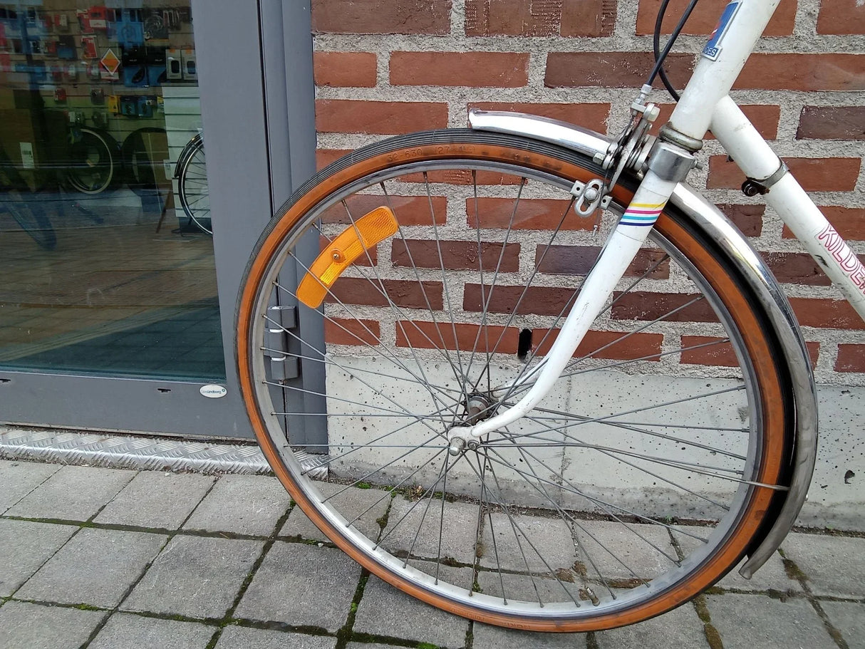 Framhjul på vit cykel med orange däck, reflex och kromad skärm