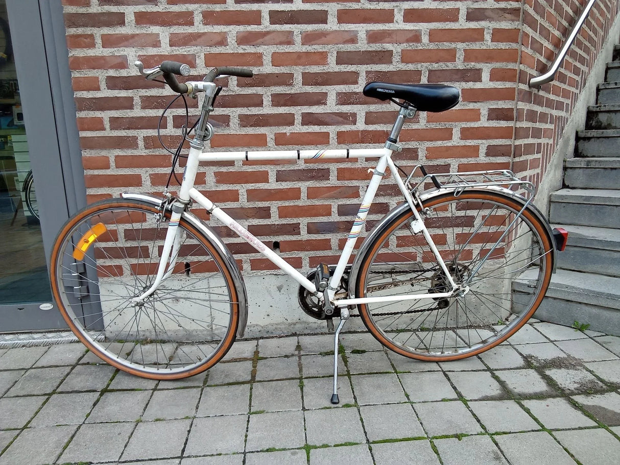 Vit vintage cykel med bruna däck, pakethållare och svart sadel