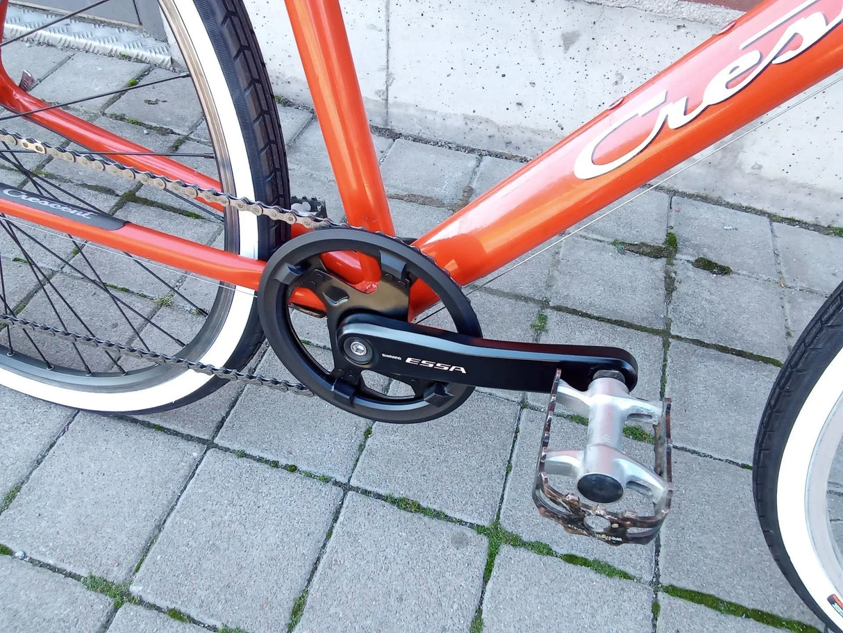 Närbild på cykelpedal och kedja på röd Crescent cykel med Shimano Essa vevparti