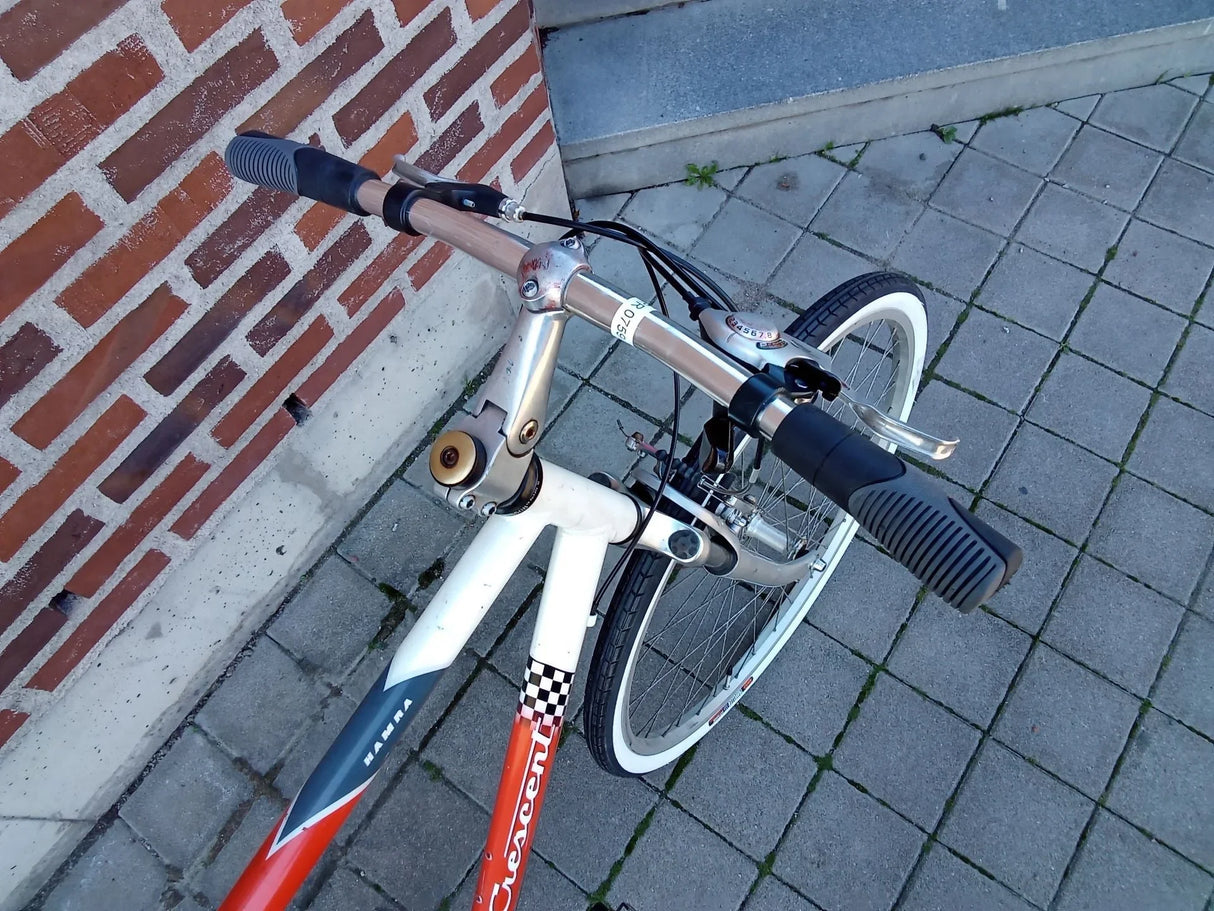 Vit och röd Crescent cykel med svart handtag och vit kant på framdäcket