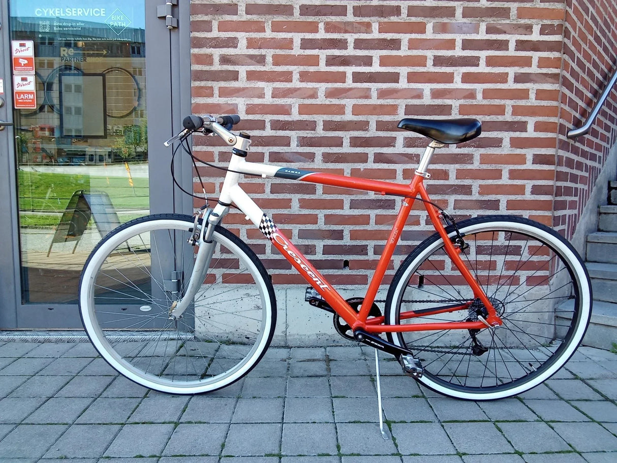 Orange och vit Crescent cykel med vita däck och svart cykelsadel