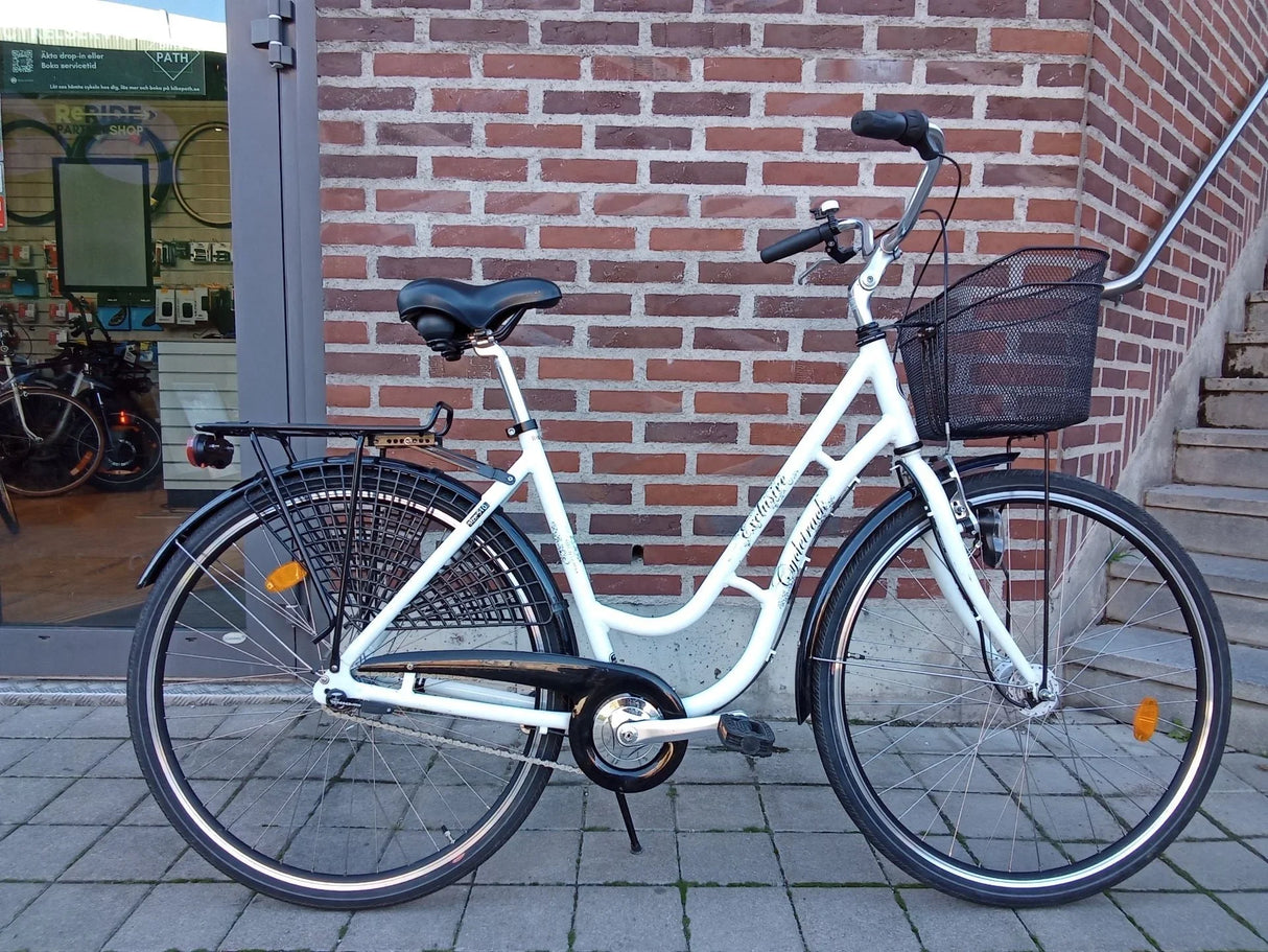 Vitt damcykel med svart cykelkorg och pakethållare