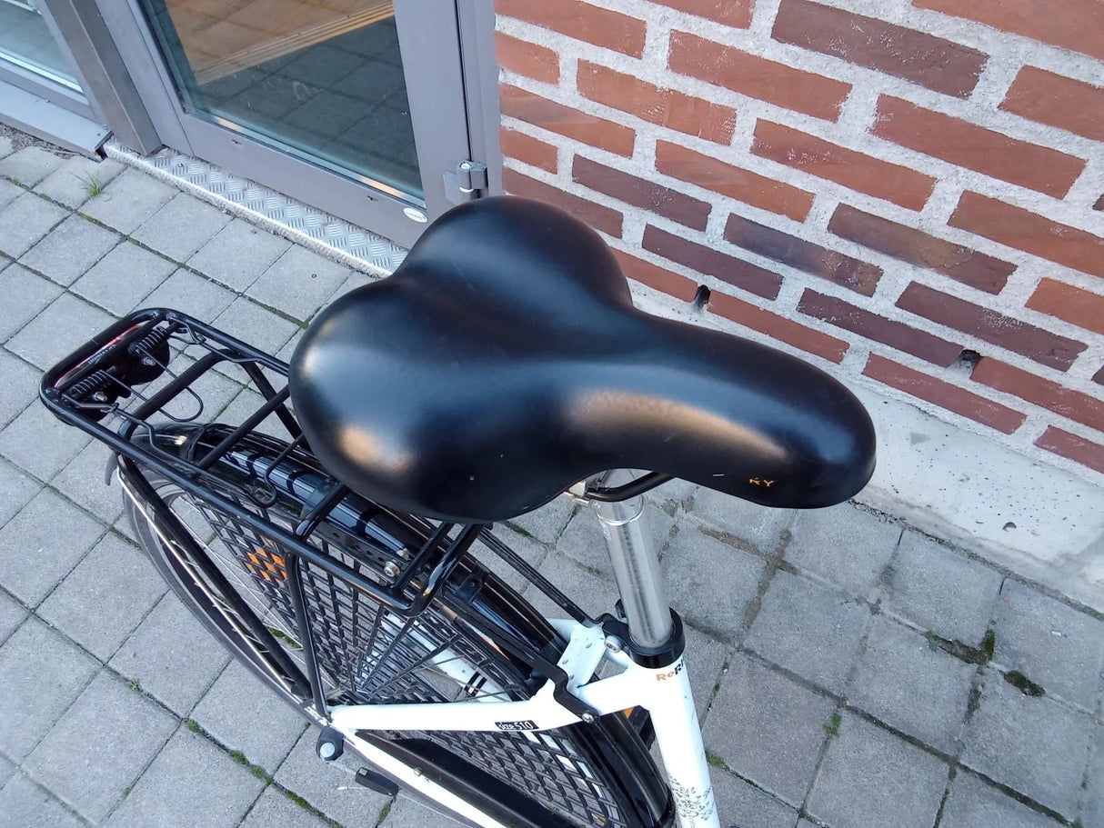 Närbild på svart cykelsadel och pakethållare på vit cykel
