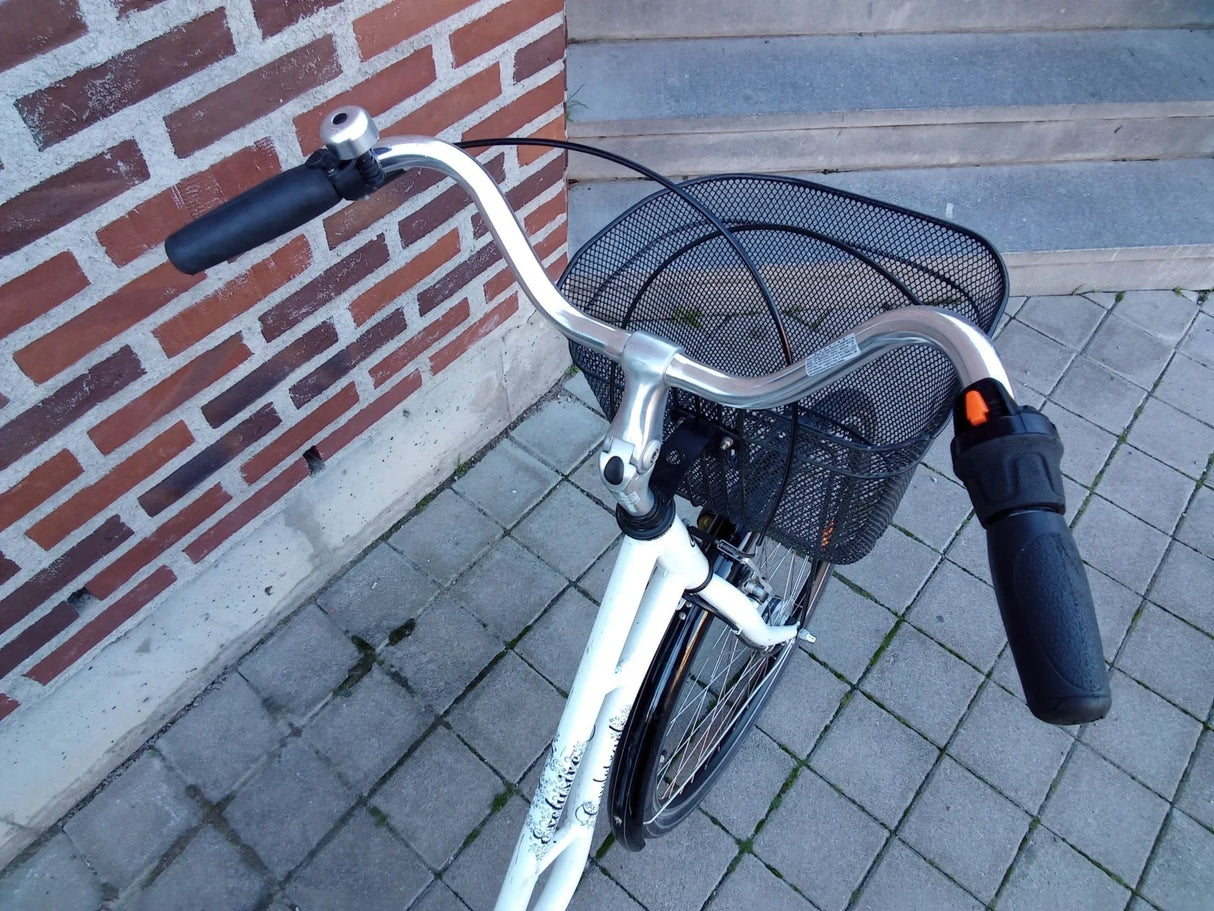 Vitt cykelstyre med klocka, svart grepp och svart cykelkorg