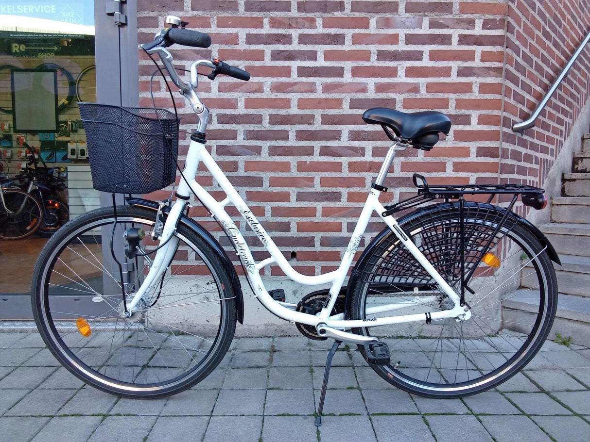 vit damscykel med svart cykelkorg och pakethållare på gatsten