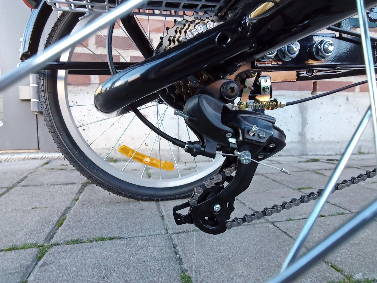 Närbild på cykelns bakväxel och kedja med svart ram och silverfärgade ekrar
