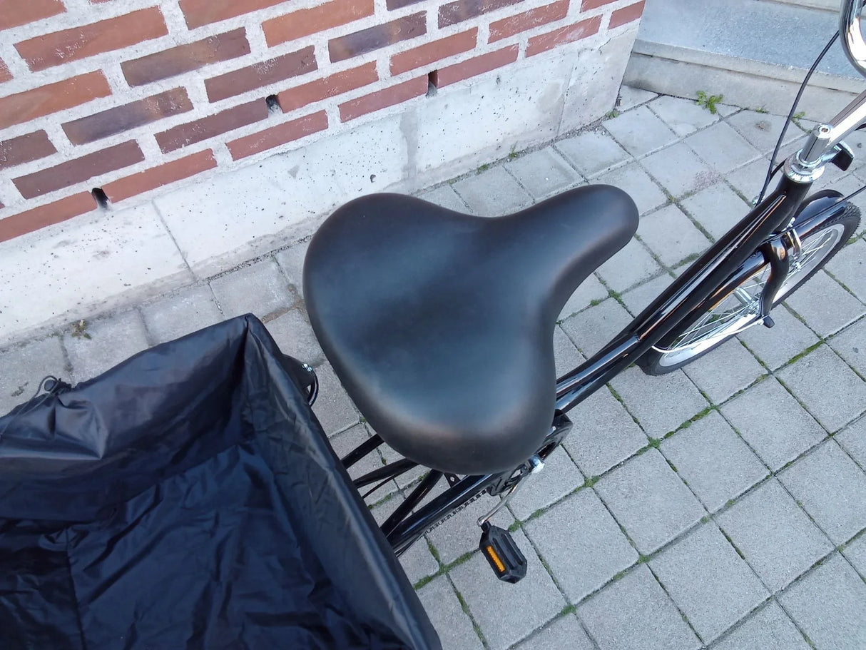 Svart cykelsadel och cykelkorg i svart textil på svart cykel
