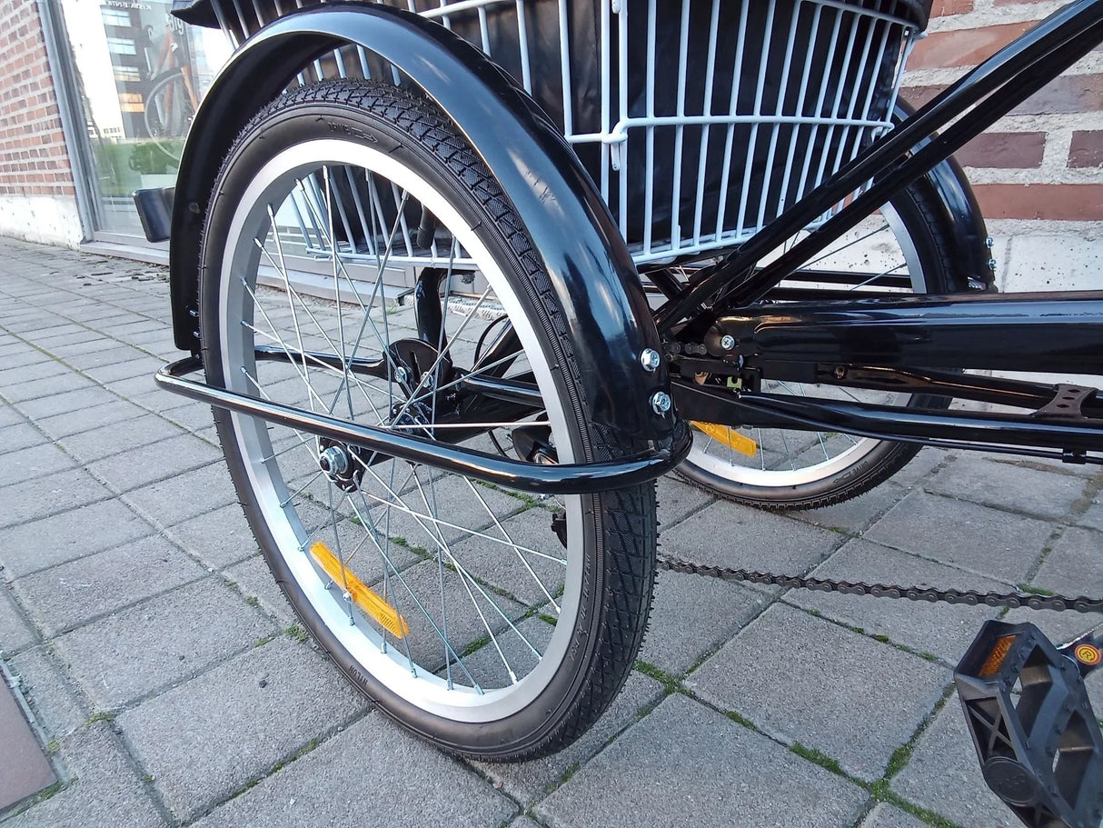 Närbild på svart lastcykels bakhjul med vit cykelkorg och reflexer