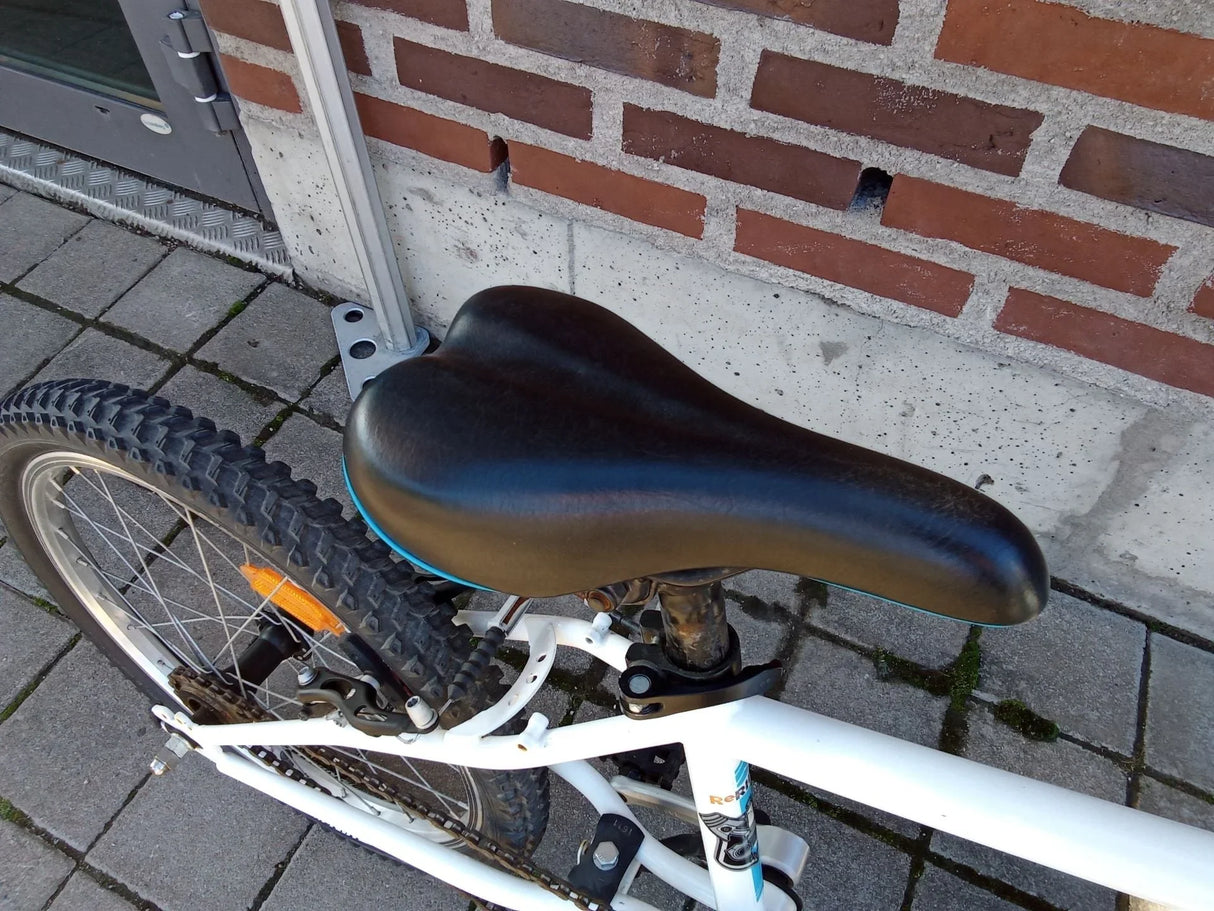 Svart cykelsadel på vit mountainbike med trögdäck på bakhjul