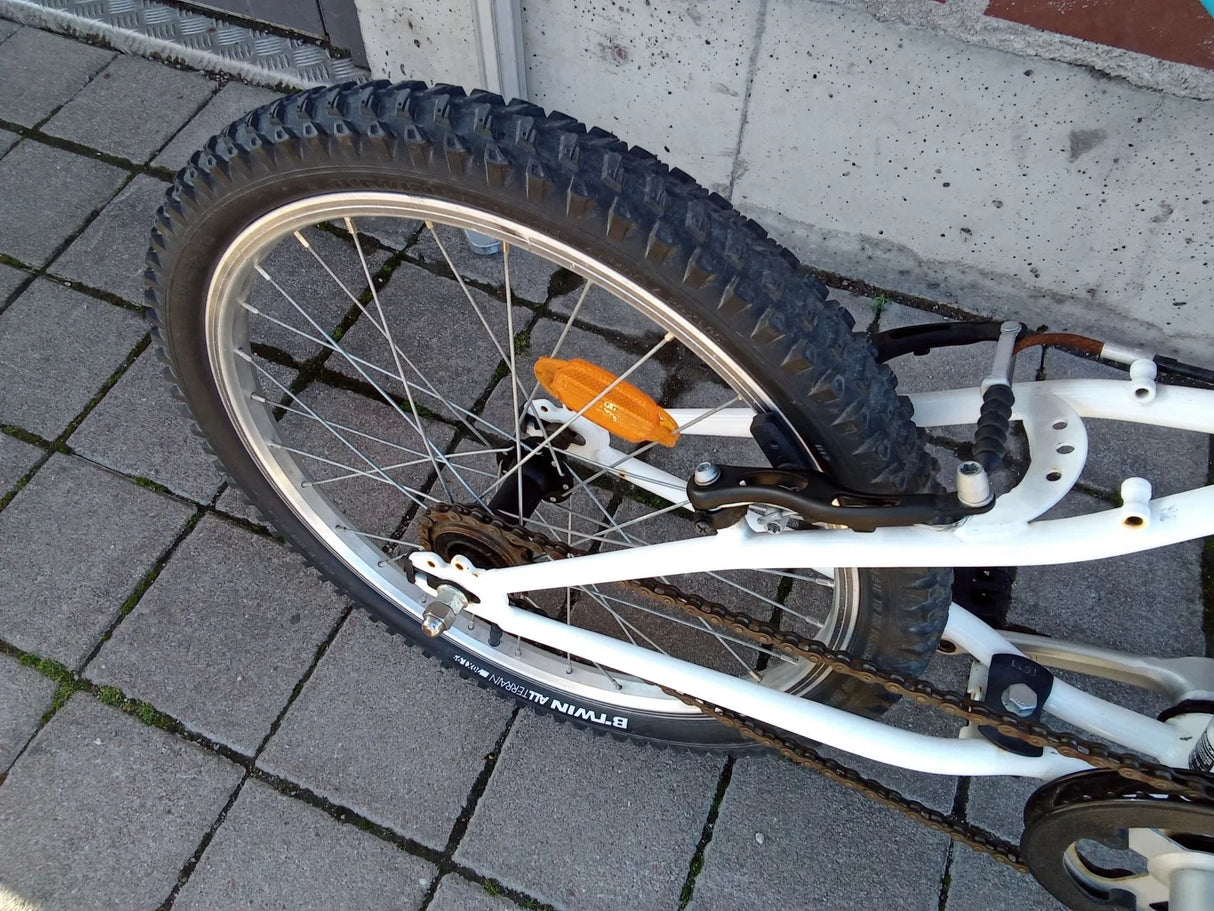Vit cykel bakhjul med B'TWIN Allterrain däck, kedja och orange reflex