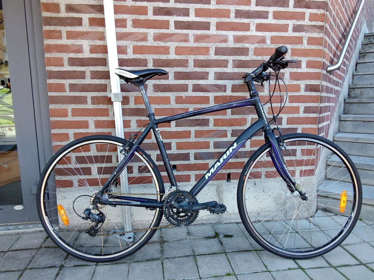 Marin hybridcykel med svart och blå ram, vita däckkanter och reflektorer
