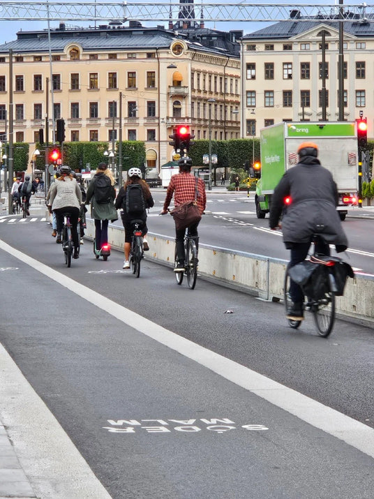 Cyklister på cykelbana i Stockholm, cykelväg med Söder Malm-skylt, stadstrafik och byggnader i bakgrunden