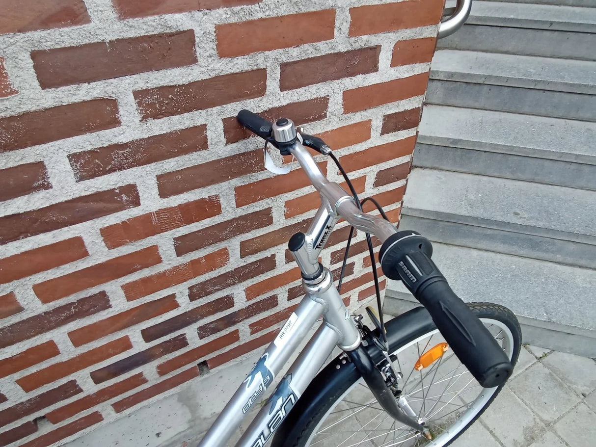 Silver mountainbike med svart handtag och reflekterande orange dell på hjulet