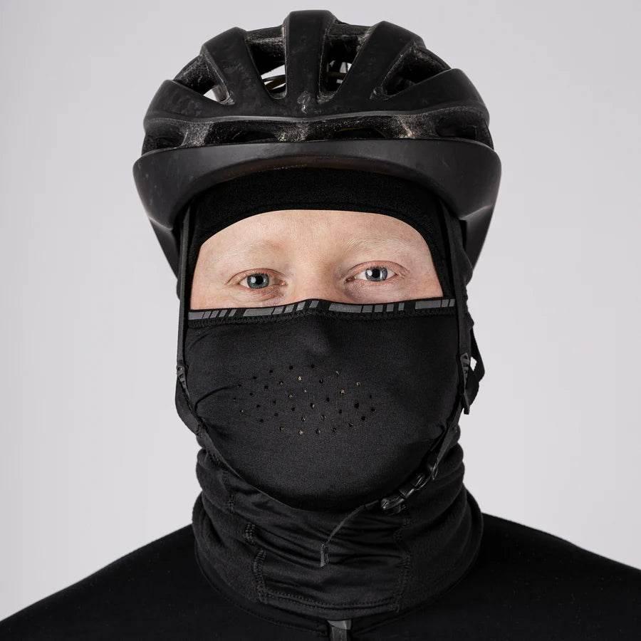 Person med svart cykelhjälm och svart munskydd med andningshål
