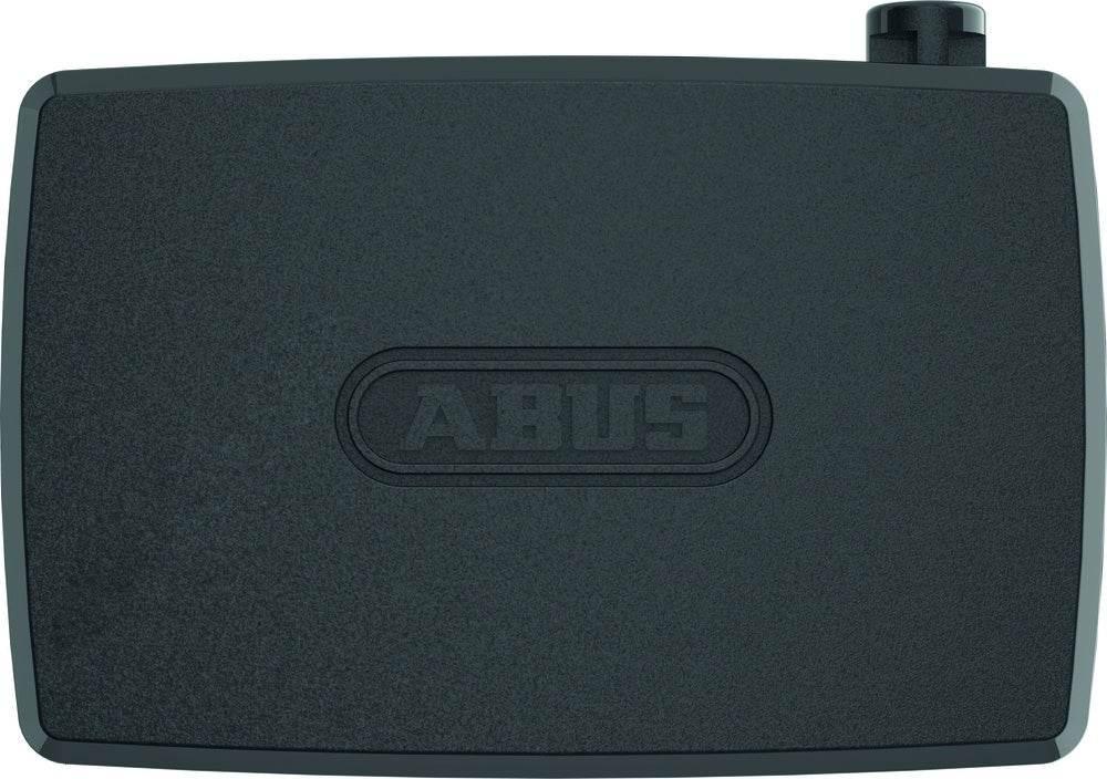 Svart ABUS-larmbox med rektangulär form och rund knapp på övre högra hörnet