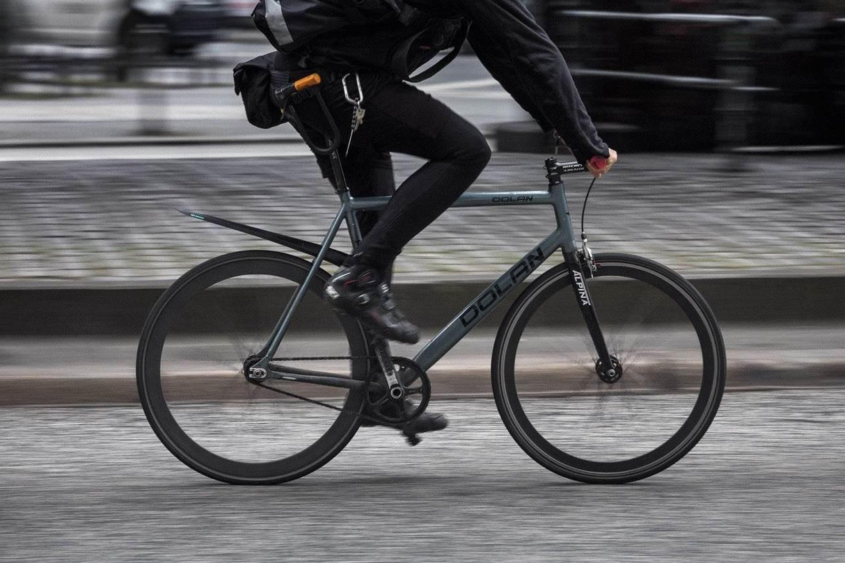 Person som cyklar en grå Dolan racercykel med svarta kläder och cykelskor