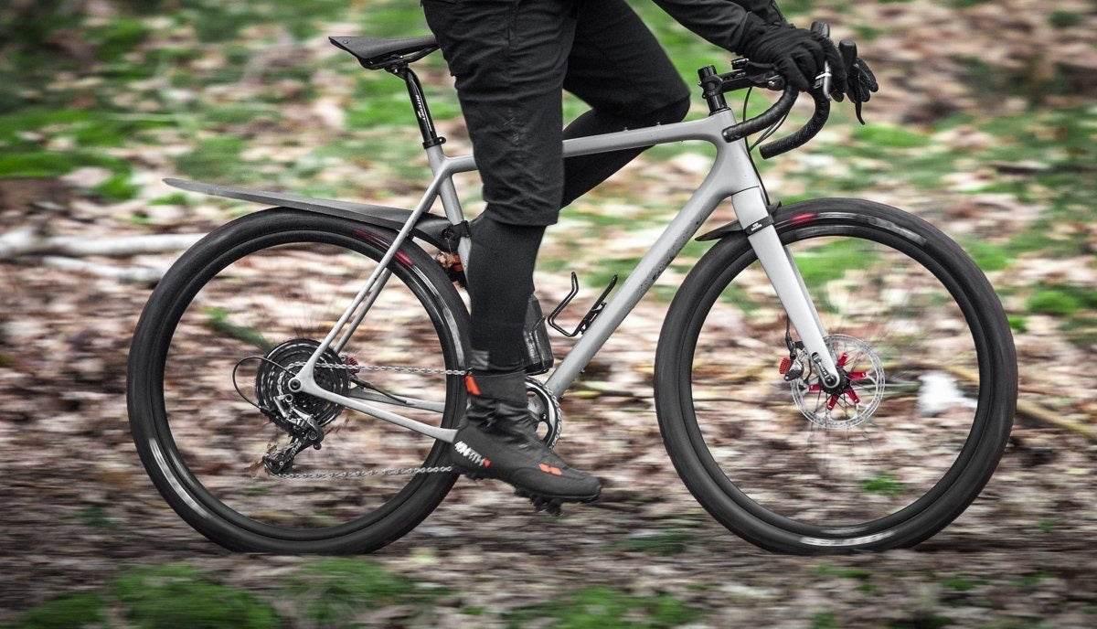 Person som cyklar på grå landsvägscykel med skivbromsar och breda däck