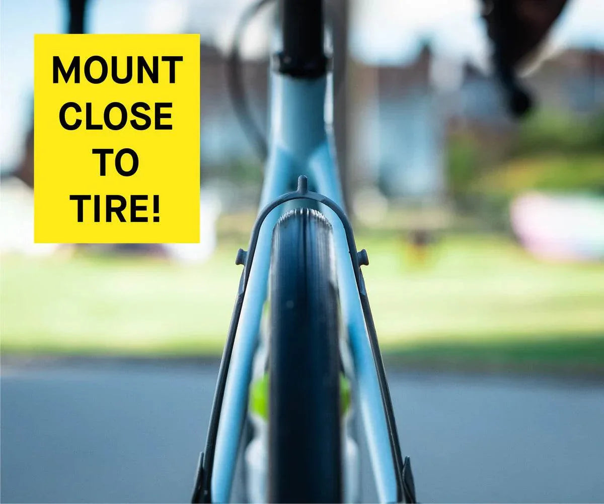 Närbild av cykeldäck monterat nära ramen med gul skylt "Mount close to tire!"