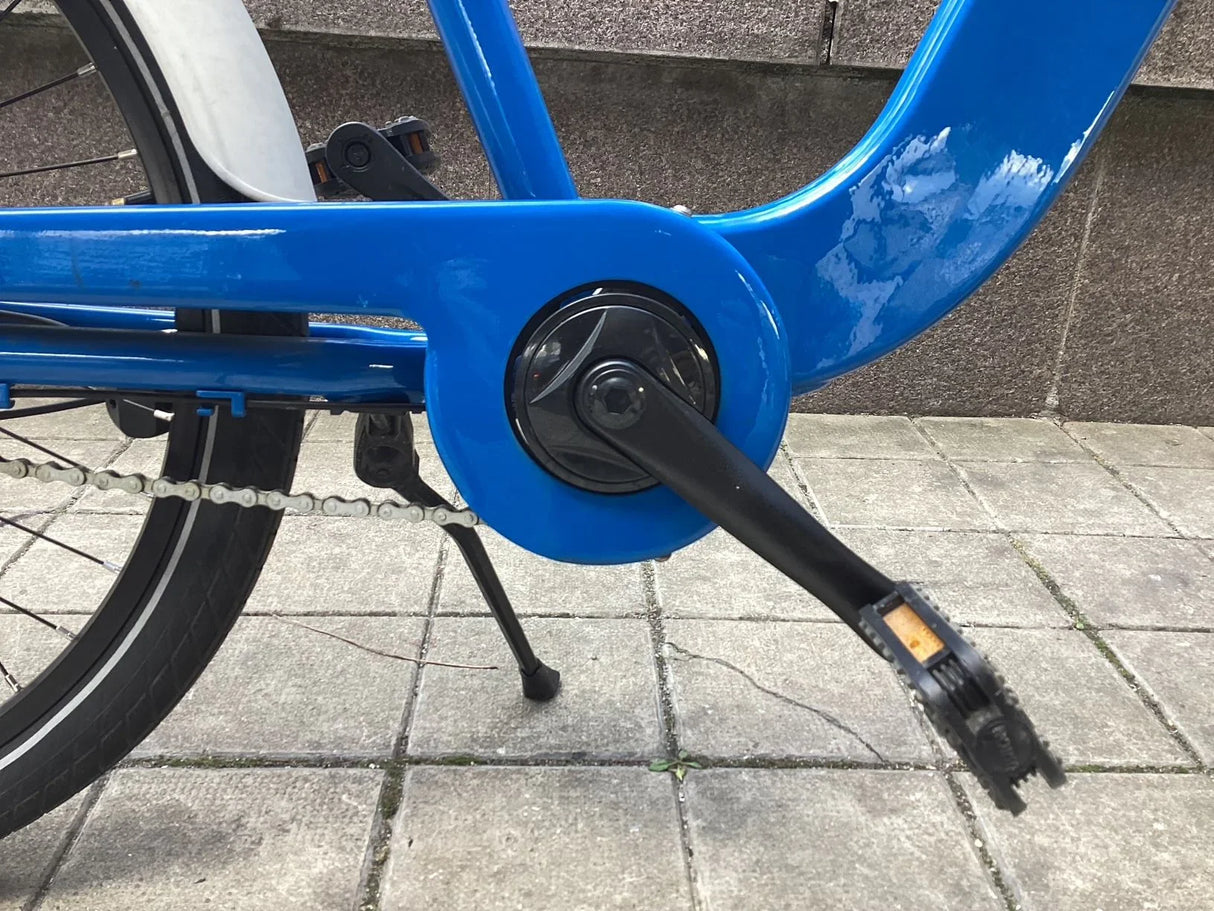 Blå cykelpedal med svart vevarm och kedja på stadscykel