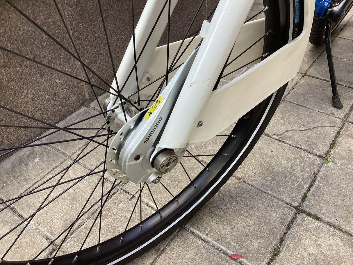 Närbild på cykelhjul med Shimano nav och vit cykelram